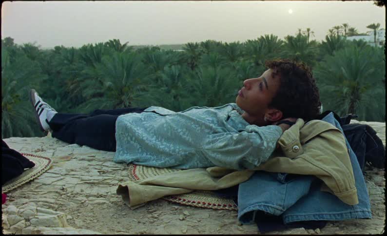 Person lying among clothes with a forest in the background