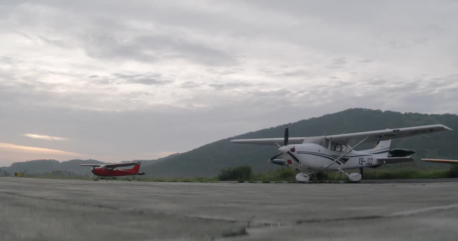 Two small planes sitting on the tarmac in front of mountains