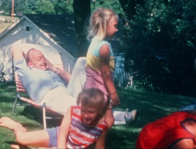 A father is watching his children play in the yard