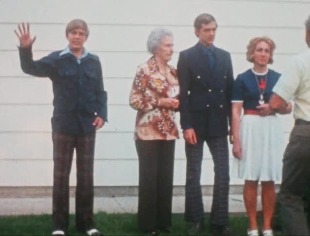A well dressed family standing on a lawn in front of a white building posing for a picture