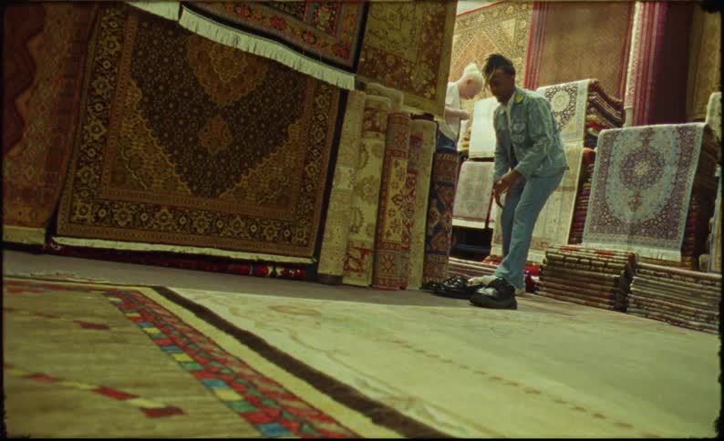 Man stands near empty shoes in a warehouse and examines rugs