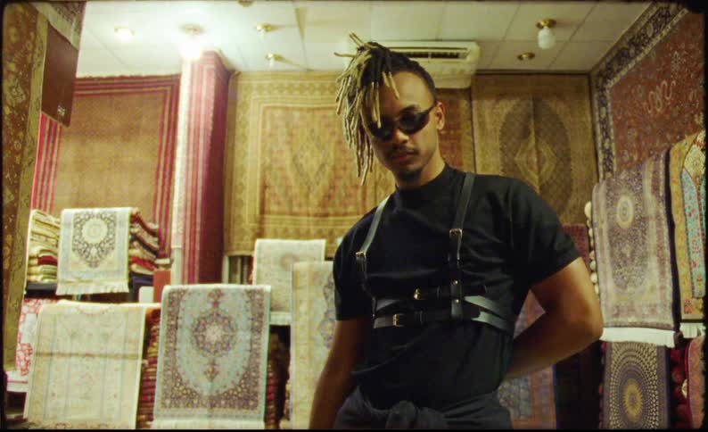 A man is posing in front of a room full of rugs