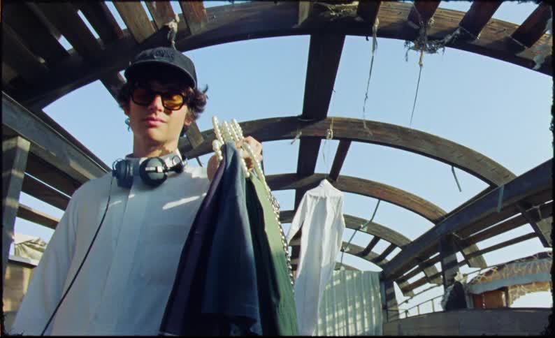 A clip of a teenager holding clothes in an hanger