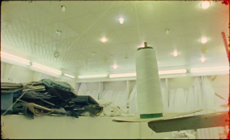 A large spool of thread sits on a table in a cluttered sewing workshop