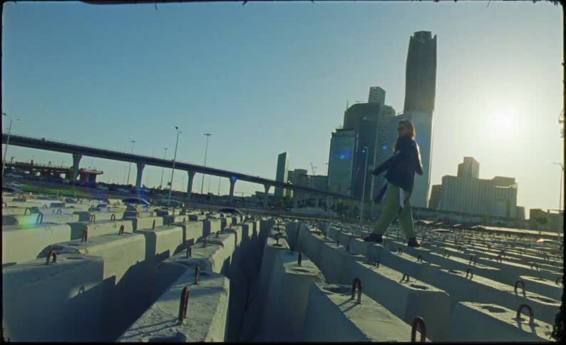 A woman walks over the slabs of concrete before the city