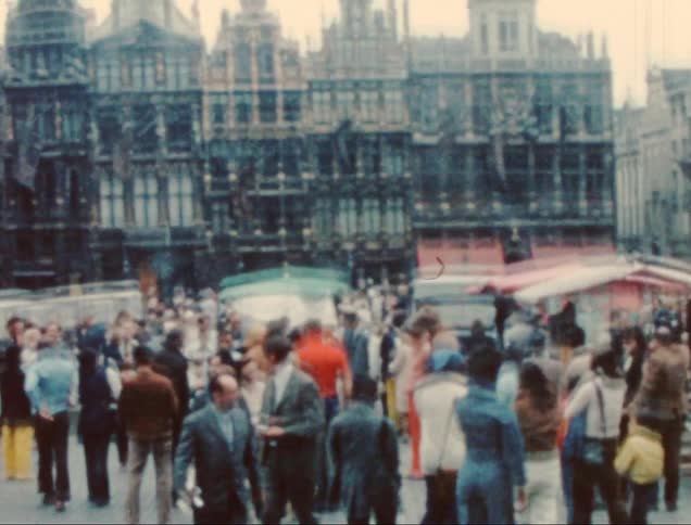 A crowd of people walk through the town square