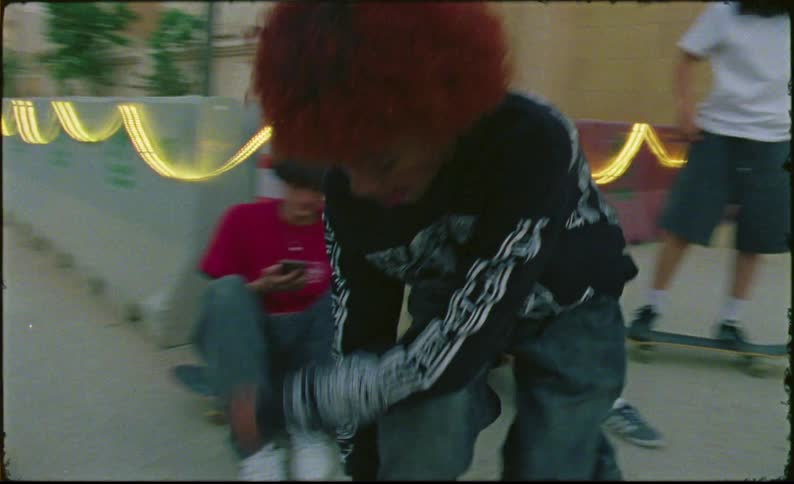 A group of teens clap while a friend skateboards in front of them