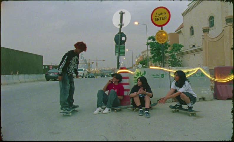 Four teenagers with skateboards with one of them doing tricks