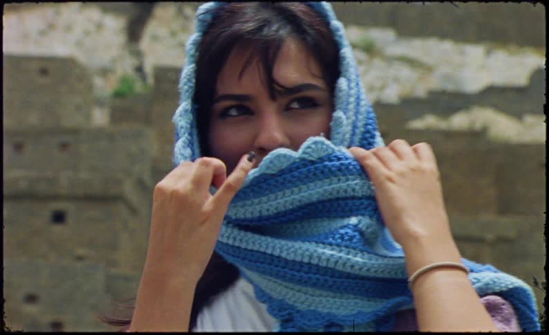 Portrait of a young woman putting a blue scarf on her face
