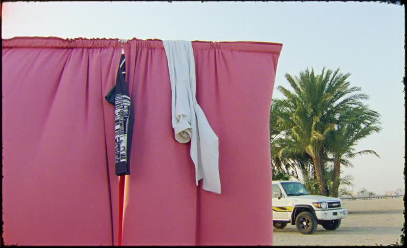 A person throws a white shirt over a pink curtain