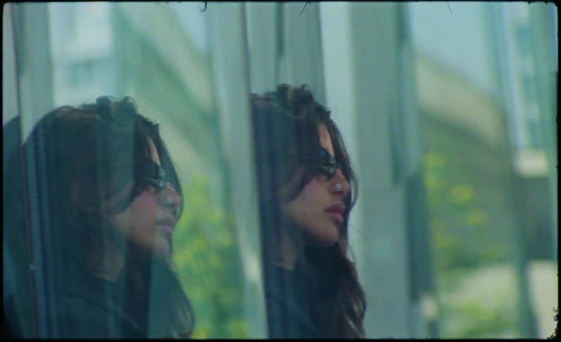 Multiple exposure reflection of a black haired woman wearing sunglasses