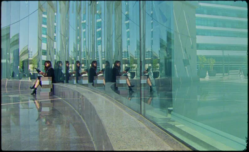 A woman is sitting on a bench outside the building