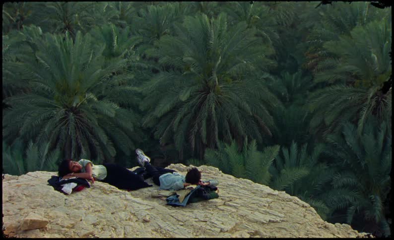 Couple laying on the cliff overlooking a jungle