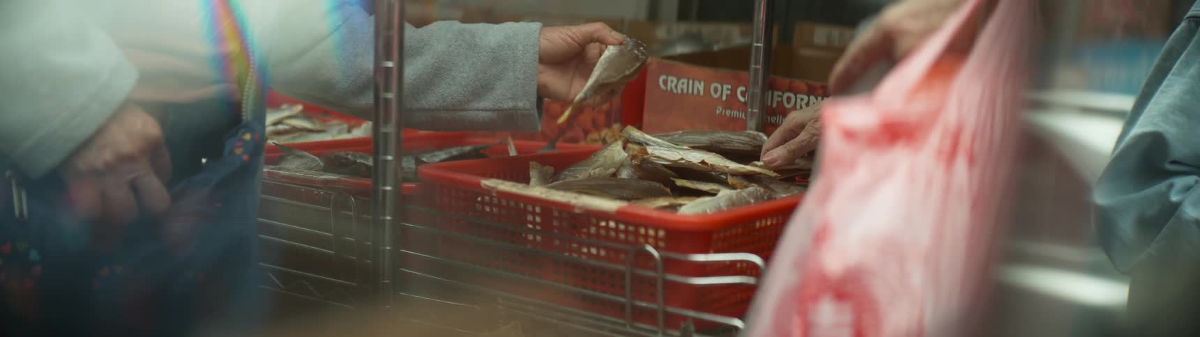 A woman is picking up dried fish inside a market