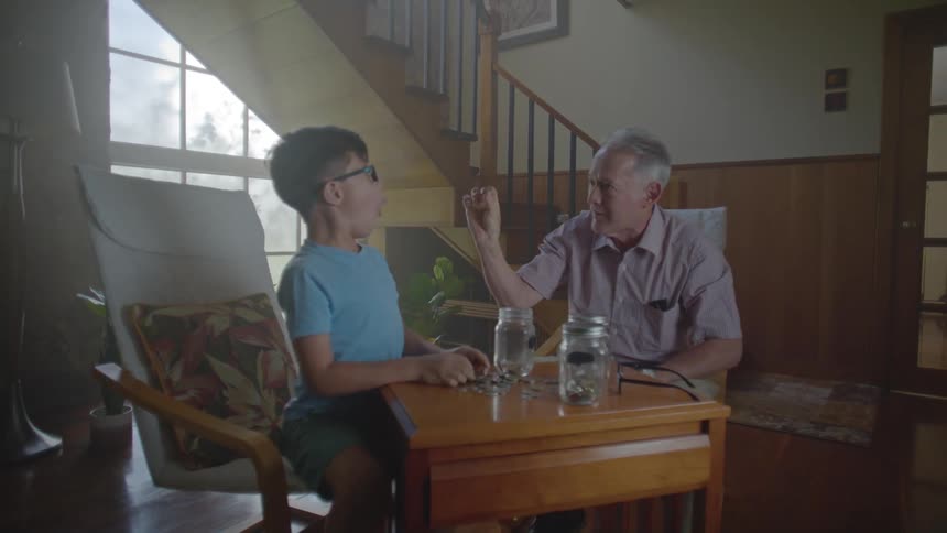 A grandfather pulls a coin from his grandsons ear in an old magic trick the child is amazed