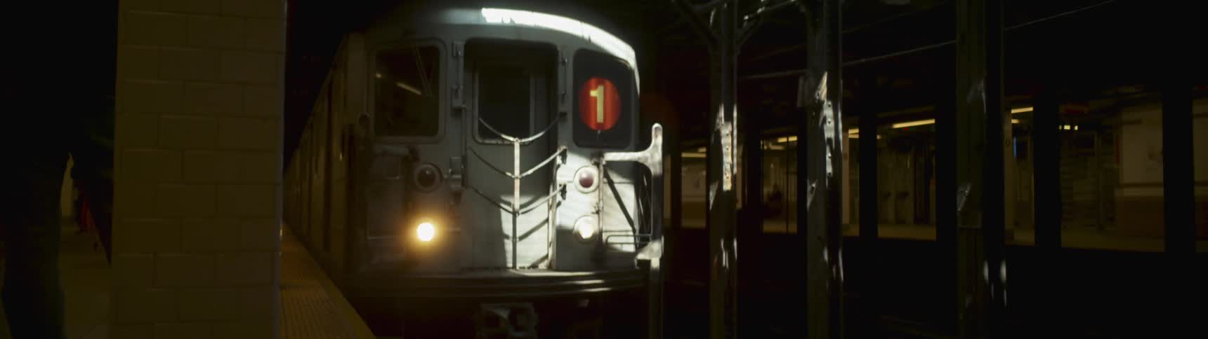 A commuter train is moving through a station at night