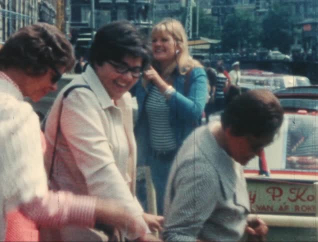 A group of people near a canal boarding boats in a lively and touristy area
