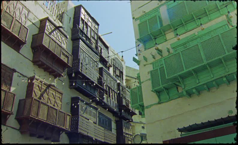 A white apartment building with some green objects on its exterior
