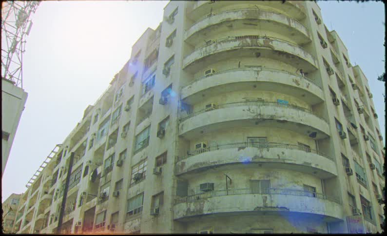A yellow corner building and its all old with a round balcony