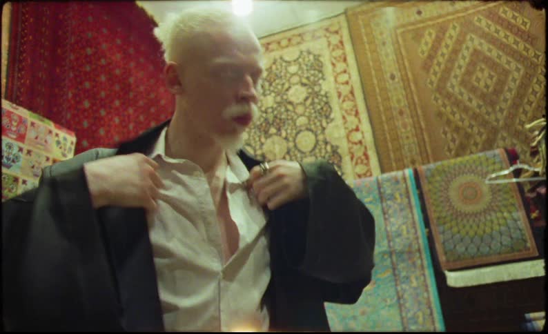 Two men in a carpet store trying on formal clothes