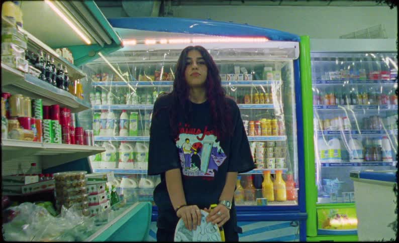 A teenage girl with a skateboard stands in a convenience store
