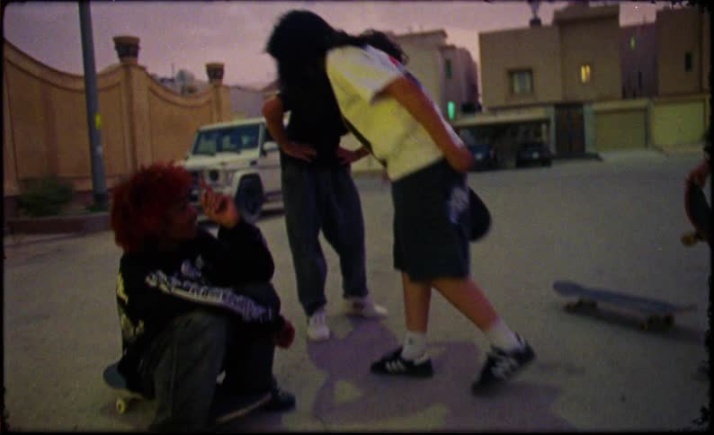 Teenage friends talking in a group and holding skateboard