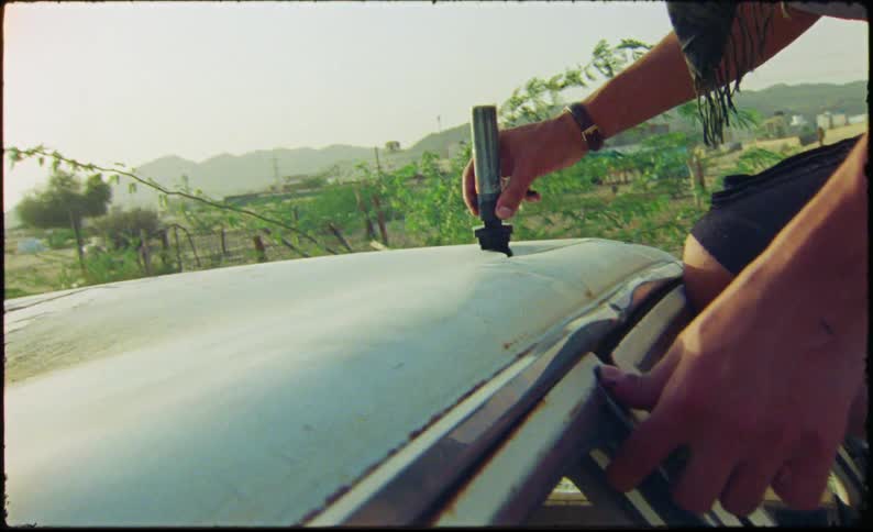 A man is painting on top of the car