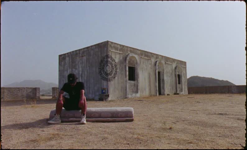 A man is sitting outside of a bunker