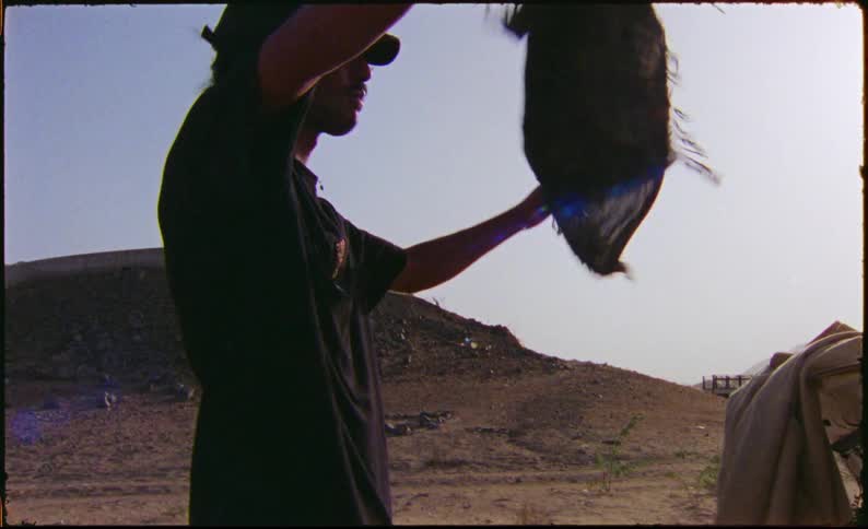 Man pulls fabric from the trunk of a car parked in a rural area near the hills and puts it on