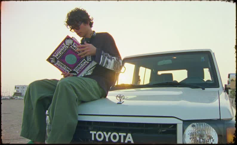 A clip of a male sitting on a car