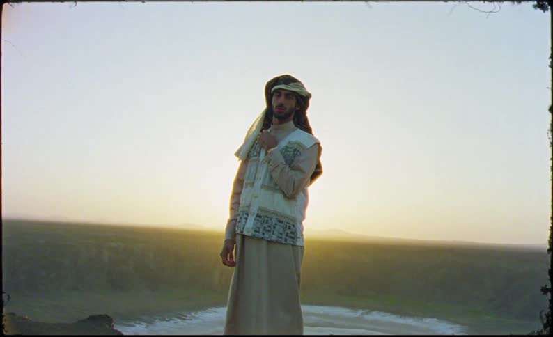 Man in arabic costume on a mountain with sunrise on the horizon
