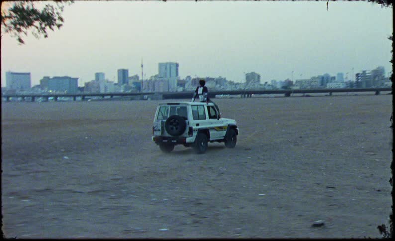 Man sitting on the roof of a moving white jeep