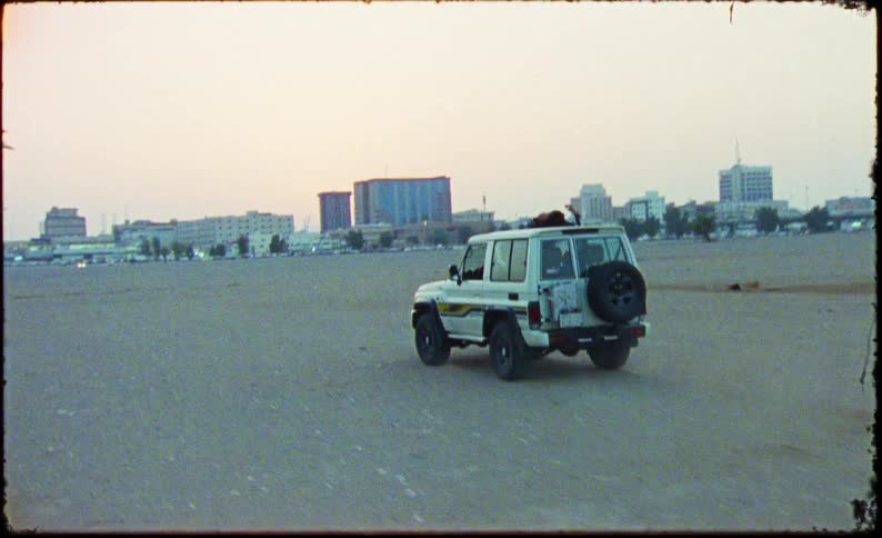 Jeep in motion and a person on the roof outside lying down