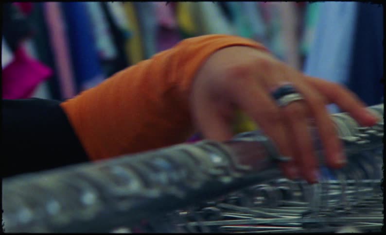 A close up clip of a persons hand arranging some hangers at the store