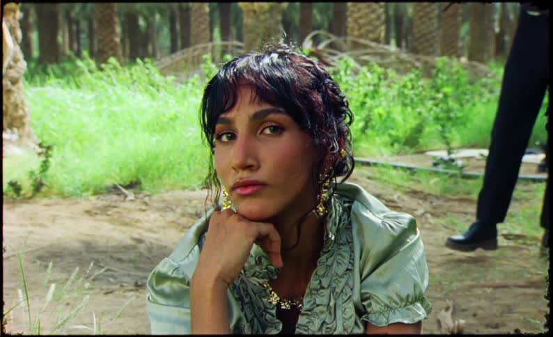 Portrait of a woman sitting and a person walking in the background