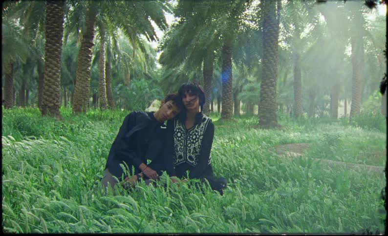 Man rests his head on a womans shoulder while they sit in the tall grass