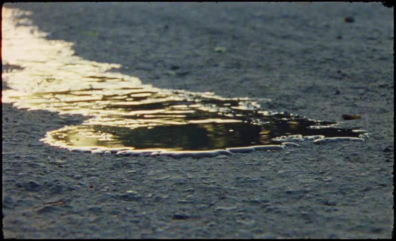 A puddle of water on a concrete floor that is expanding