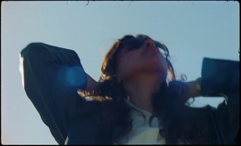 Portrait of a woman wearing a jacket and sunglasses in an outdoor setting