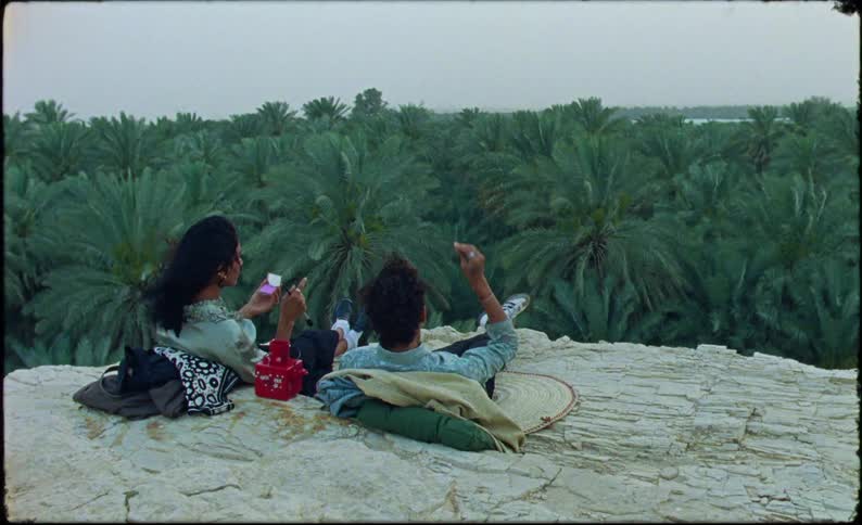 Man and woman lying on a hill throwing stones in a tropical forest