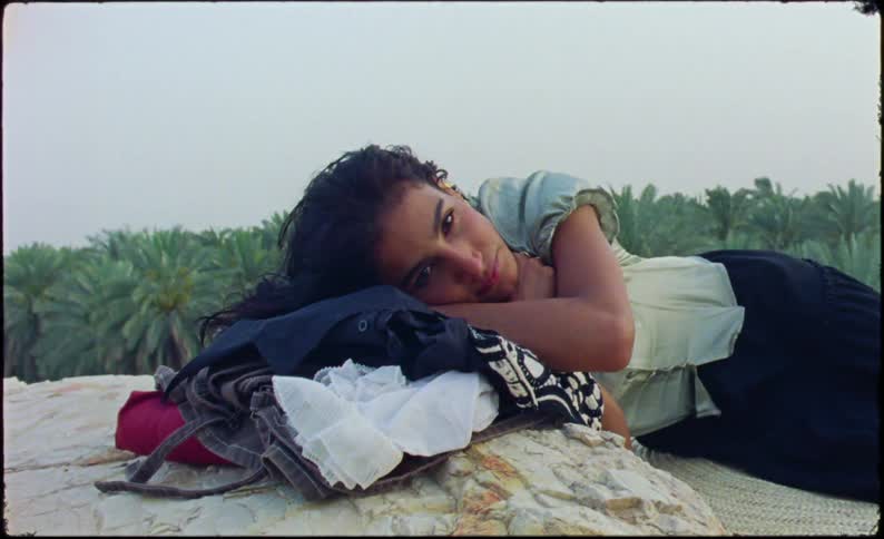 Woman lying in clothes on a rock with a tropical forest in the background