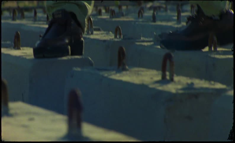 Person walks on concrete bases with curved rebar sticking out the top