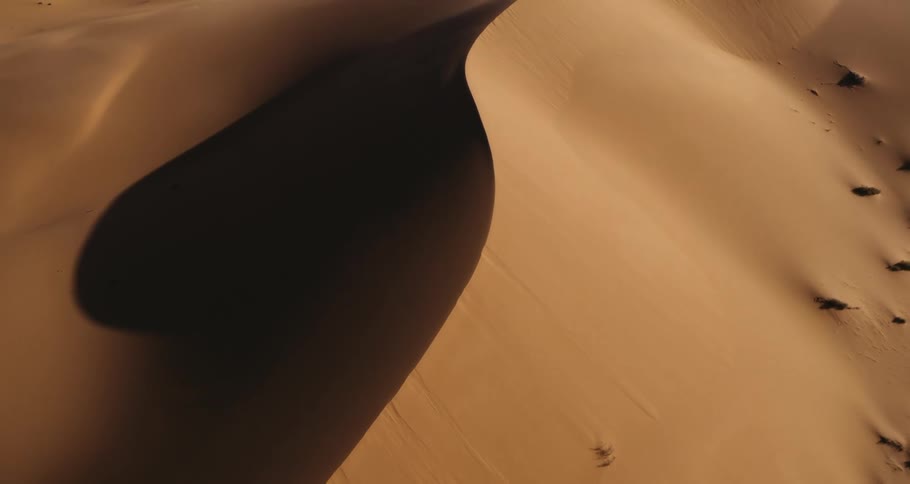 A drone moves up revealing a golden desert landscape in the empty quarter, abstract and beautiful