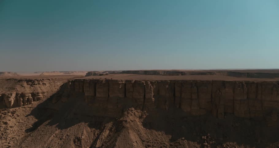 A wide show of a desert cliff edge which reveal a large desert expanse