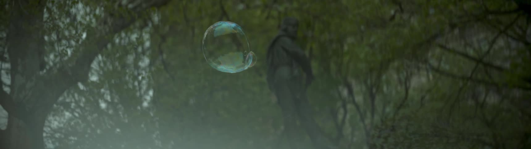 A bubble floats through the air with a statue in the background