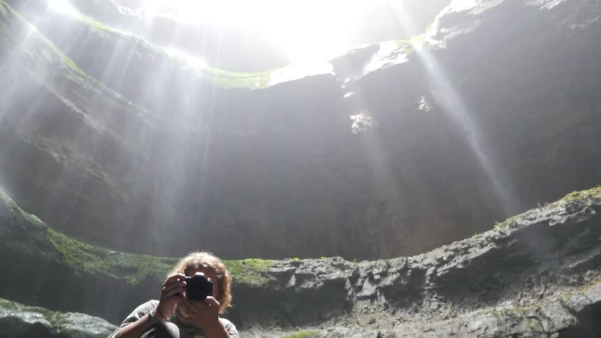 Person crouching holding a camera in a cavern