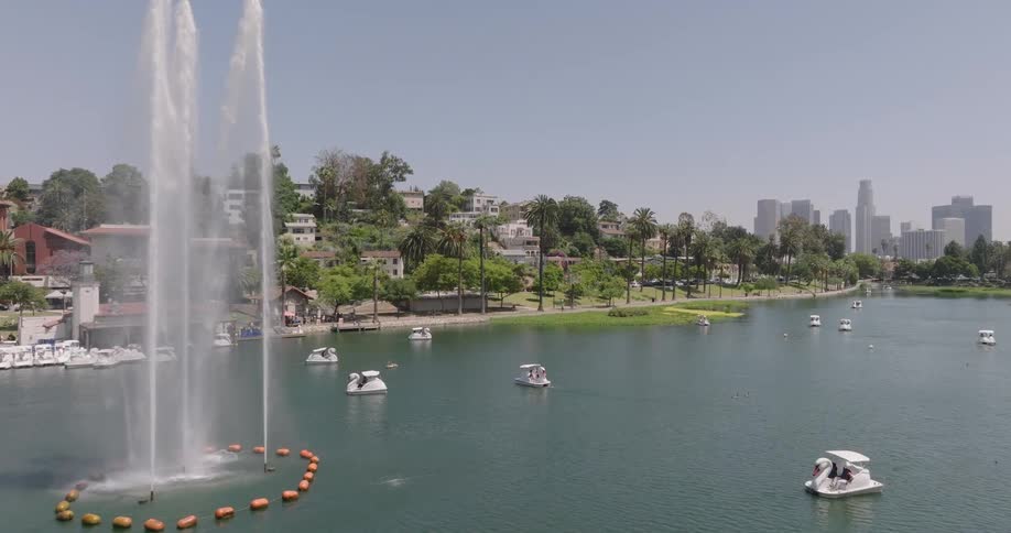 Echo park lake in los angeles with a large fountain in the center and the city skyline in the distance