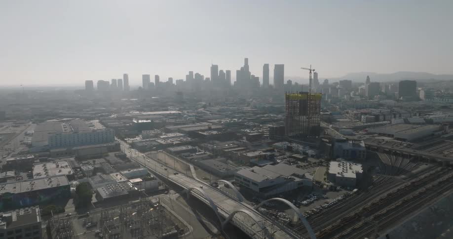 An aerial view of a cityscape with a prominent skyline of tall buildings a partially constructed highrise and a network of roads and railways