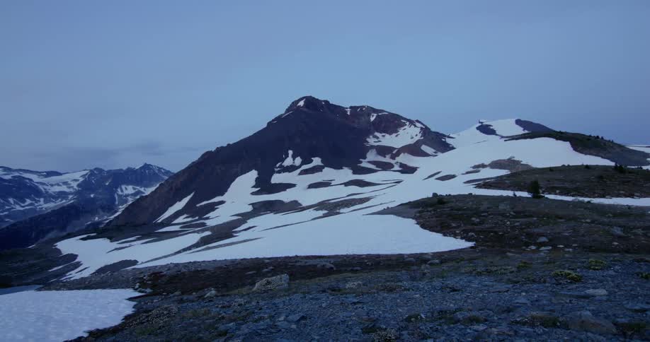 A mountain peak is partially coated in snow