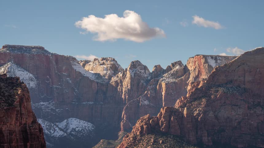 Mountain range with snow and clouds passing by