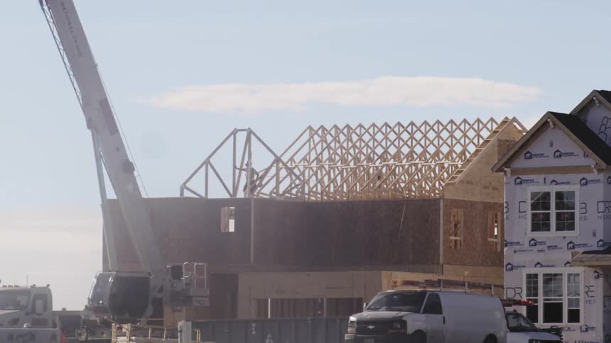 People on a construction site building the top of a house